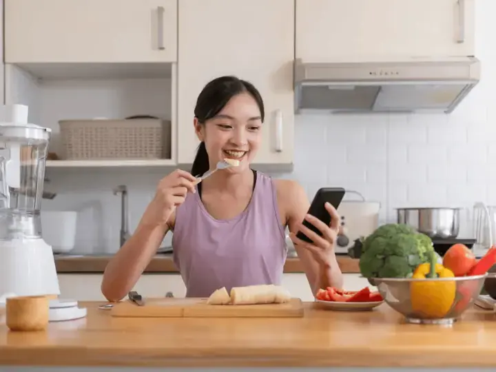 A woman enjoying a slice of banana while looking at her phone